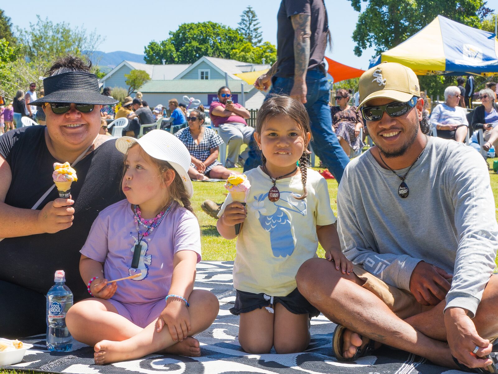 A family sitting together on a blanket with ice creams