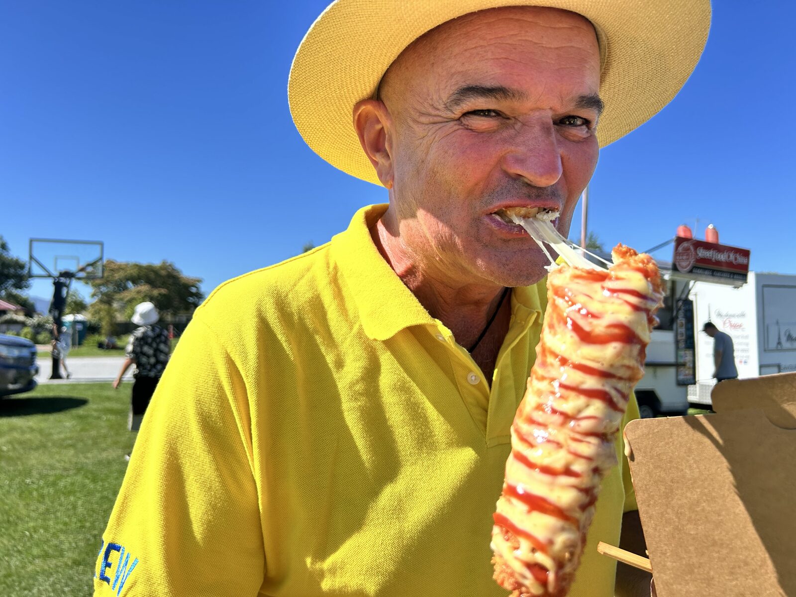 A visitor enjoying a spiral potato from a food cart